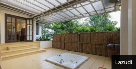 Covered outdoor patio area with a built-in spa bath and garden fence