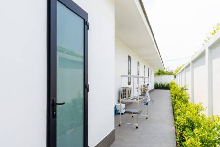 Narrow outdoor corridor with exterior doors and garden border