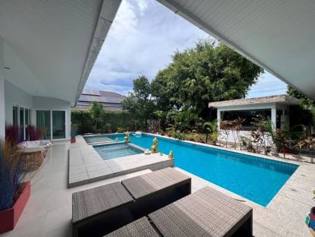 Outdoor pool area with lounge chairs and adjacent garden space