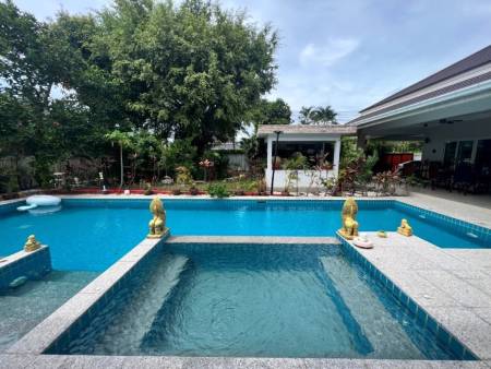 Outdoor swimming pool with decorative statues and garden view