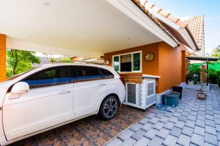 Covered carport next to house with paved driveway and outdoor units