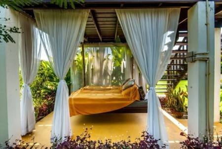 Outdoor covered patio area with a hanging bed and curtains